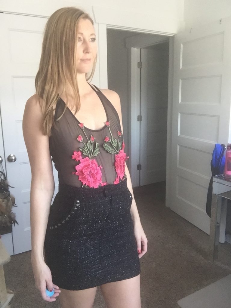 Woman in floral sheer bodysuit and black mini skirt