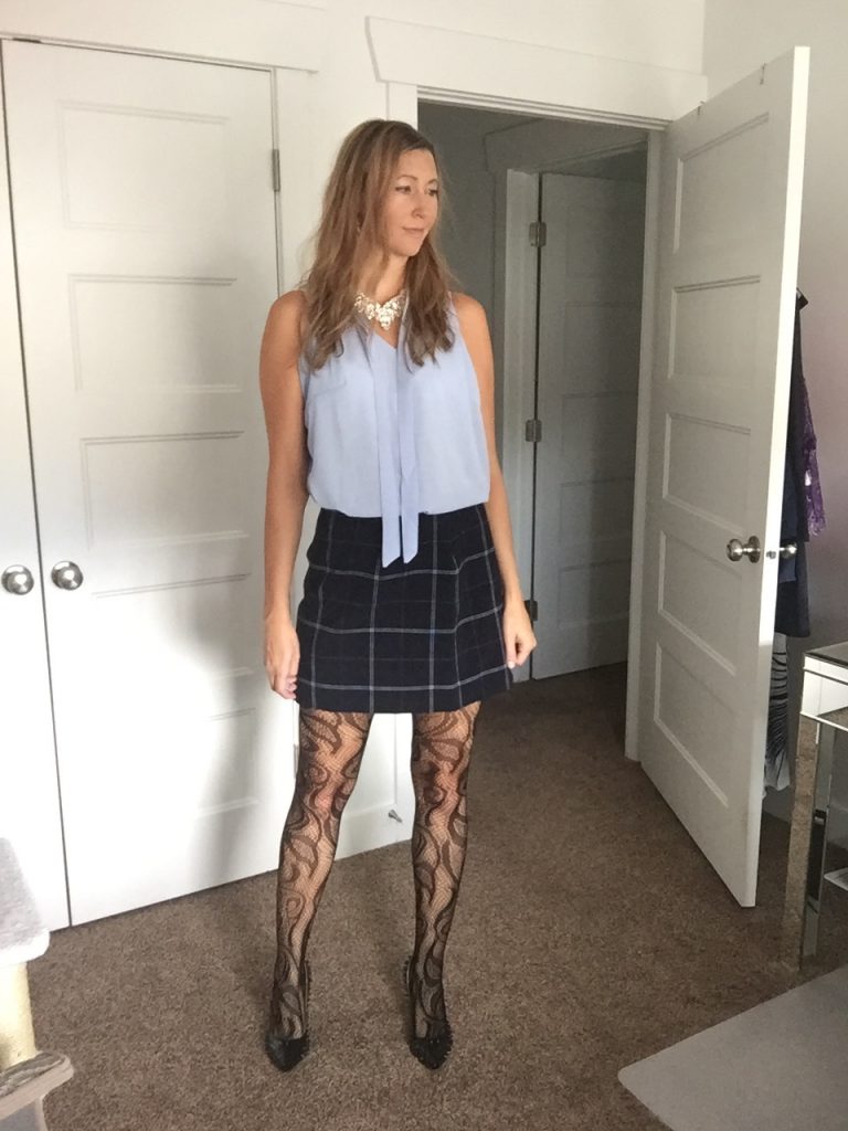 woman in Light Blue Chiffon Tie Front Sleeveless top, navy plaid skirt, and print fishnet tights